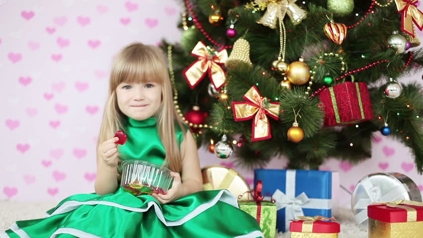 Girl is sweet. Child siting on the floor near a Christmas tree