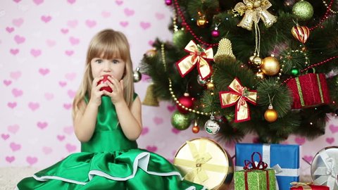 Girl eating an apple near a Christmas tree. She sits on the floor Stock Video