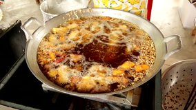 Banana deep frying in hot oil in a cast iron frying pan, FullHD - Popular street food in Southeast Asia.