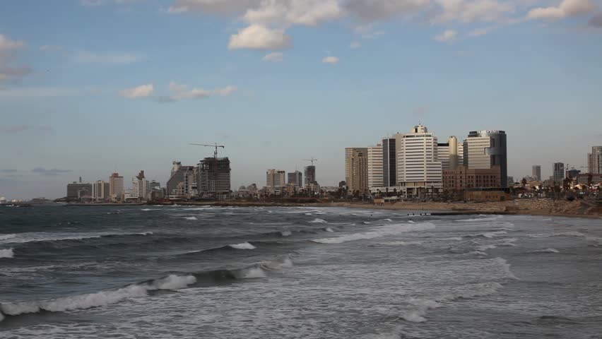 Tel Aviv skyline behind waves rolling in from the Mediterranean Sea