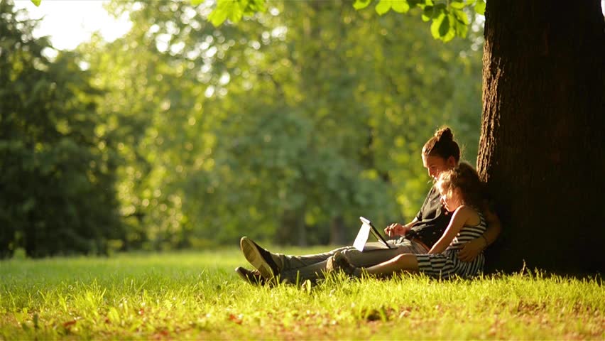 Young mother and her daughter playing on a tablet and a dog in a beautiful park | Shutterstock HD Video #17126203