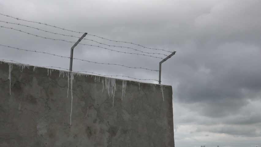 Concrete fence with barbed wire on top, prison