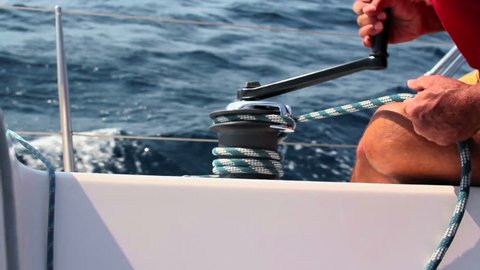 Sailing, man pulling rope, winding rope around winch
