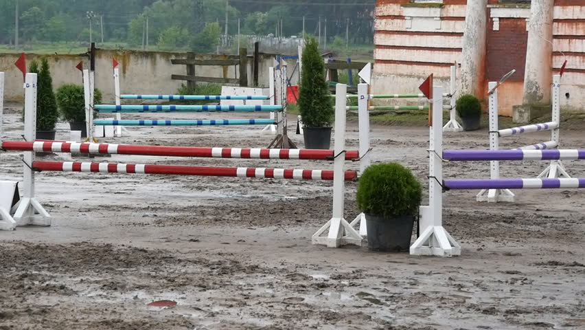 Professional female jockey rides on horseback. Horse is galloping and jumping through a barrier in competition 