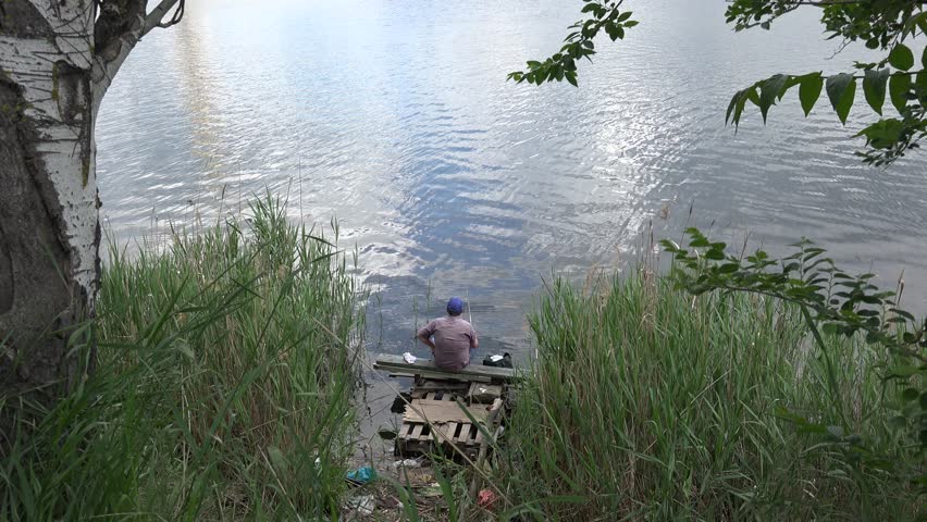 Fisherman sitting on the bank of the river among the reeds, fish, fishing spot