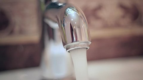 Turning off tap, close up of adult hand turning off water