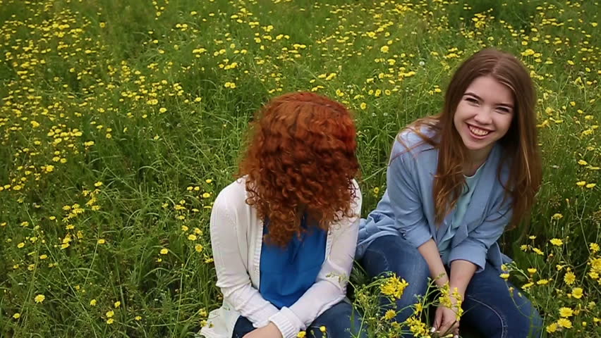 Best friends forever. Friends sitting in the meadow. Girls laugh. Slow motion. The concept of friendship.