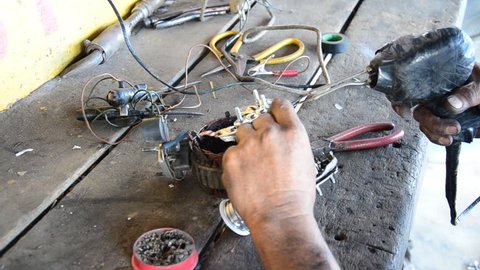 Old man 60 year old thai people professional automotive motor mechanic lead-free solder for repair and inspecting the alternator of car at local shop in Nonthaburi, Thailand
