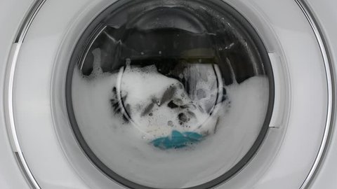Washing machine washing clothes./ Washing clothes with laundry detergent.