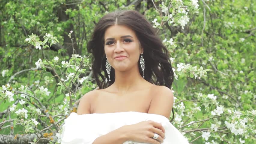 Beautiful brunette girl in a white dress in a blooming Apple orchard | Shutterstock HD Video #17153065