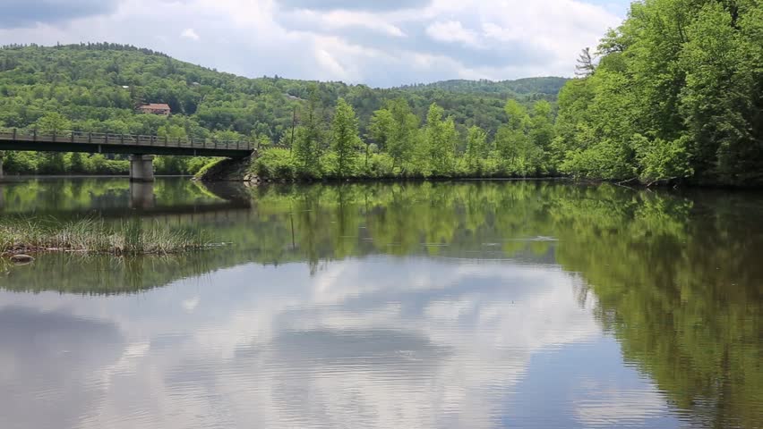 View of a river with a forest. road and bridge in the background in Vermont.