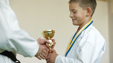 boy receive karate trophy and medal for the victory