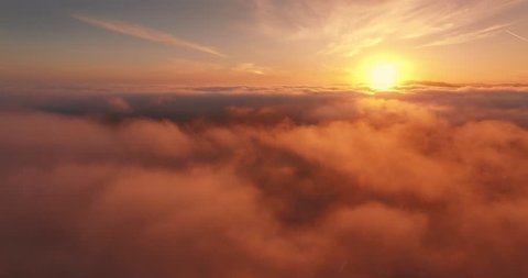 Aerial view of epic low clouds moving over Pacific Coast in California at sunset. Camera flying backward. 4K UHD