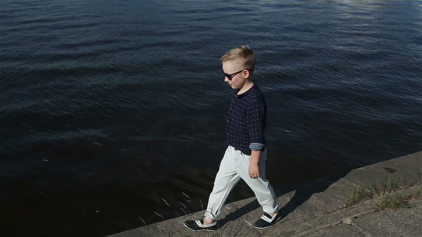 baby boy blond 8 years in a blue shirt, light trousers