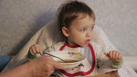 Grandmother feeds the child at home for dinner table