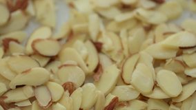 Close video of sliced almonds being poured onto a plate.