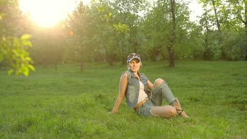 Cute girl in jeans clothes posing against the sunset.