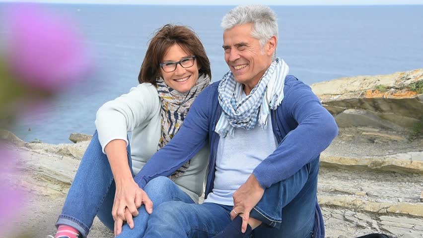 Senior couple on rambling day sitting by cliff