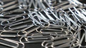 Metal or steel wire clips for documents in office on wooden table close-up slow tilt 4K 2160p 30fps UltraHD footage - Wire steel paperclips with looped shape 4K 3840X2160 UHD tilting video