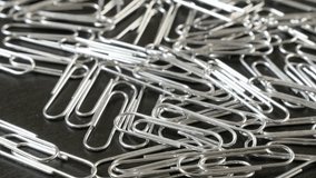 Lot of metal or steel wire clips for documents in office on wooden table close-up slow tilt 4K 2160p 30fps UltraHD footage - Wire steel paperclips with looped shape 4K 3840X2160 UHD tilting video