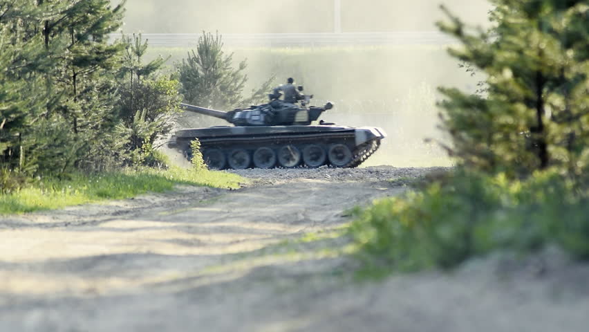 Tanks moving on the road through the forest. Tanks moving on the road through the forest. Military people are sitting on the tank armor. Towers of tanks deployed in the opposite direction. Slow motion