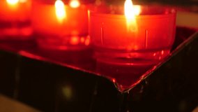Tilting on Catholic prayer red cup votive candles in candle rack 4K 2160p 30fps UltraHD footage - Lot of wax votive candles arranged in church slow tilt  4K 3840X2160 UHD video