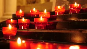 Many Catholic prayer red cup votive candles in candle rack 4K 2160p 30fps UltraHD footage - Lot of wax votive candles arranged in church 4K 3840X2160 UHD video