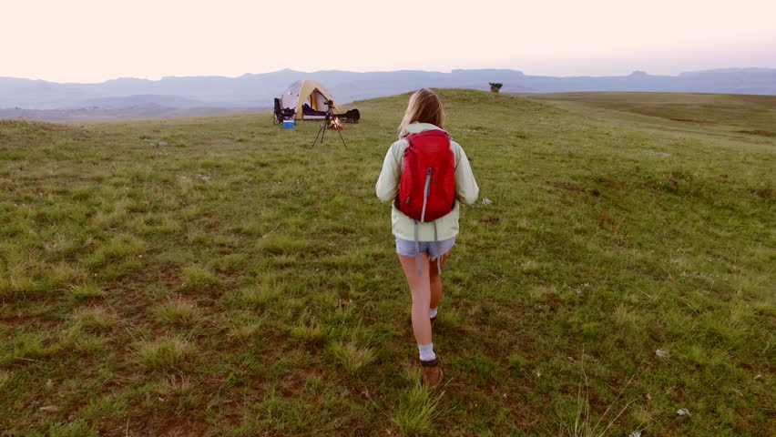 Magical drone footage of healthy woman traveler walking towards camp being on epic camping adventure in African mountains.