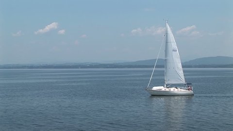 A sailboat drifts across vast blue lake