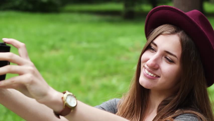 Beautiful Girl Tourist Makes Selfie on Old Film Camera. the Woman is Very Beautiful. She is Wearing a Gray Dress. in Terms of Many Green Trees.