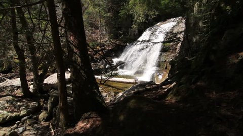 Hiker walks on nature trail, admires waterfall