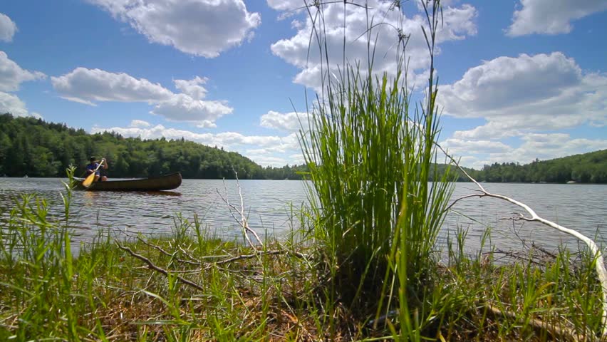Boy paddles across lake in canoe