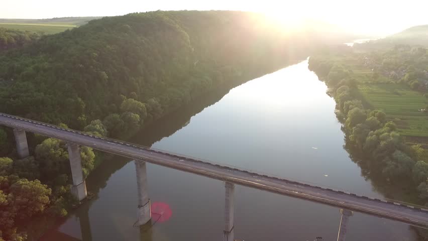 Aerial view. Flight over the river and bridge. Sun dusk. Amazing view green tree.