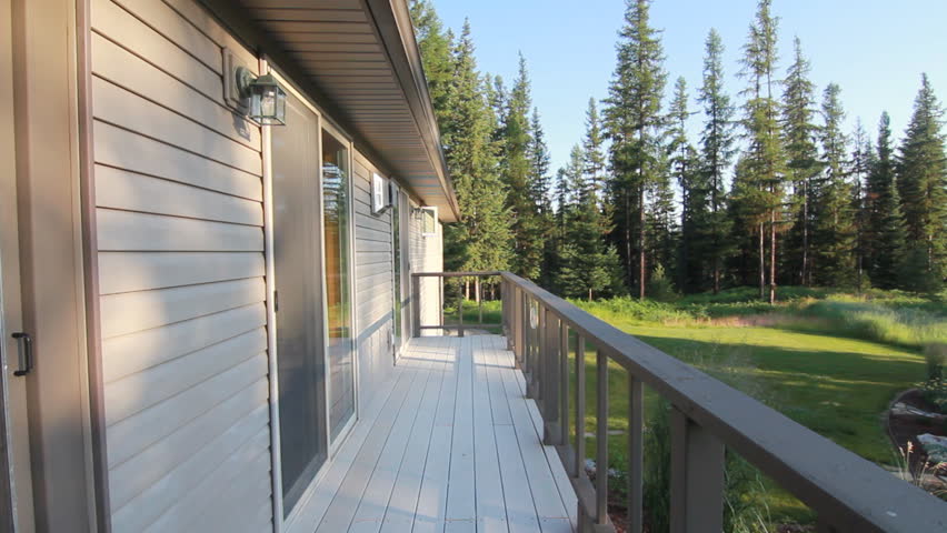 Exterior of house balcony overlooking garden and pine tree forest