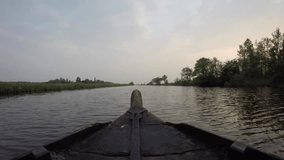 Bow of wooden boat gliding on serene river in late afternoon. - Powered by Shutterstock - Get 15% off with code: PIKWIZARD15