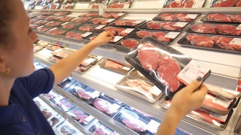 Young Woman Choosing Meat in Supermarket