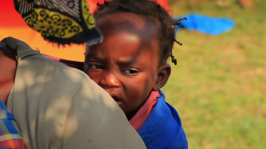 KENYA, AFRICA - CIRCA 2011: Baby on mother's back looking into the camera in