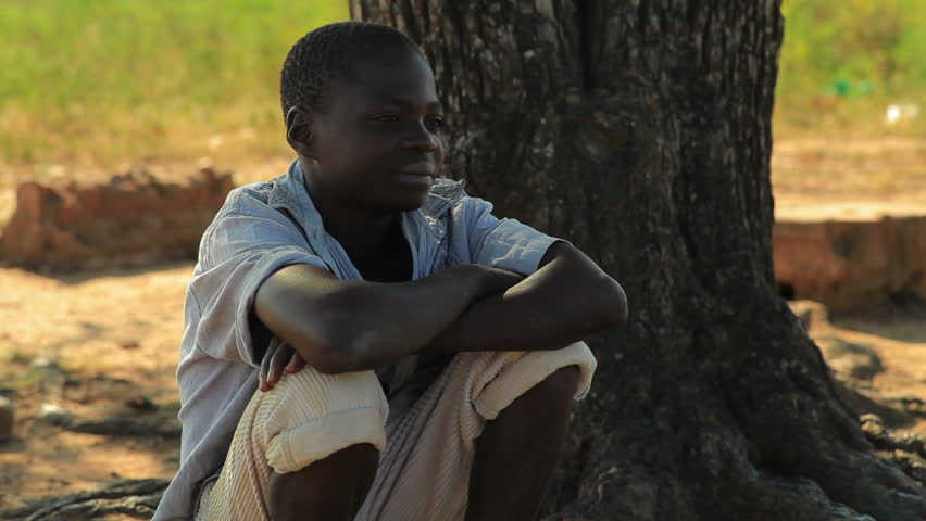 KENYA, AFRICA - CIRCA 2011:  A boy sitting under a tree thinking.