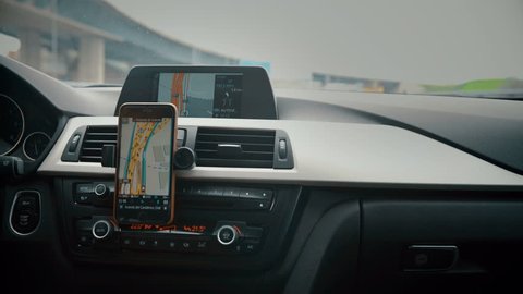 Close up on screen navigation tracking vehicle location and route while driving on road. GPS navigation on smartphone showing route.