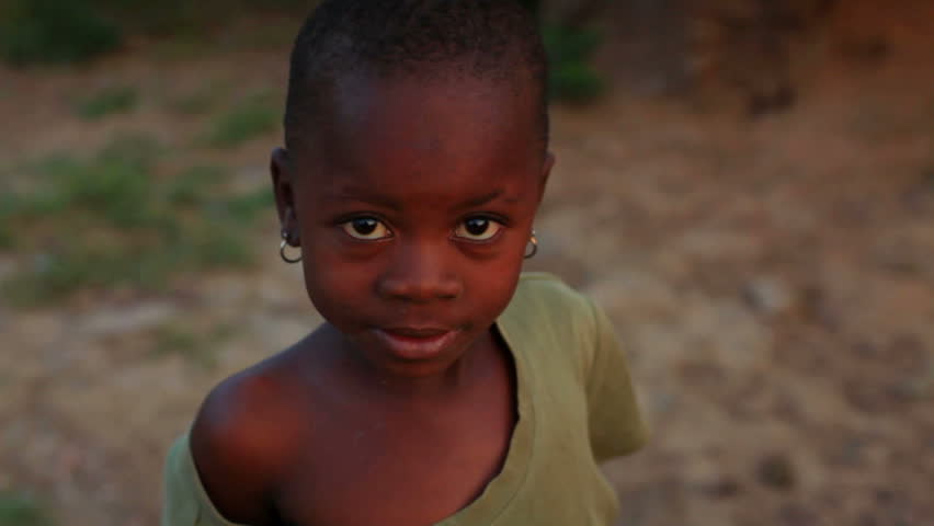 KENYA, AFRICA - CIRCA 2011: A little girl wearing an oversized shirt looking at