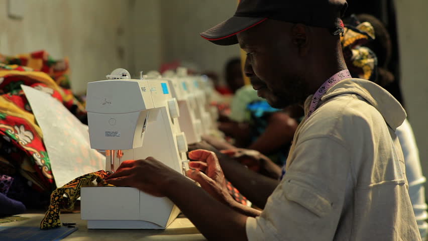 KENYA, AFRICA - CIRCA 2011: A row of women and men operating sewing machines.