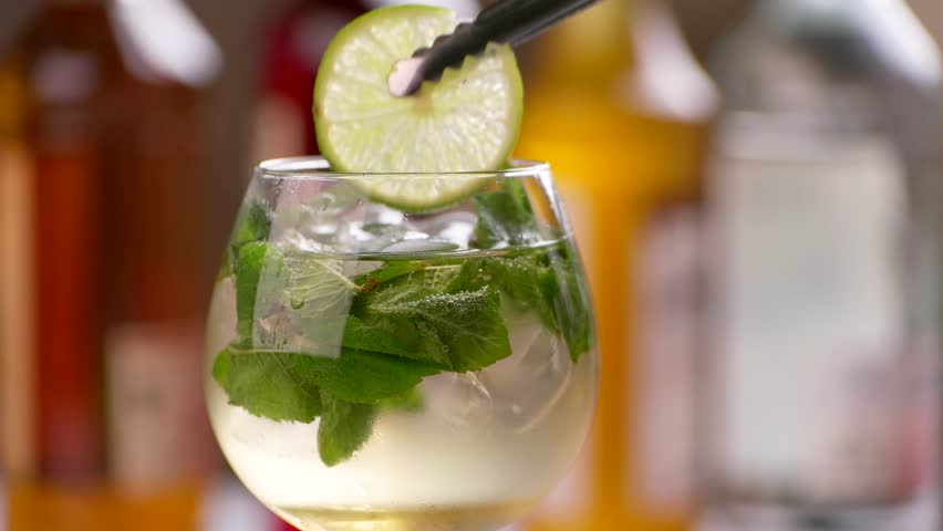 Tongs put lime into drink. Beverage with lime and ice. Hugo cocktail served at bar. Mineral water and elderflower syrup. Royalty-Free Stock Footage #17245768