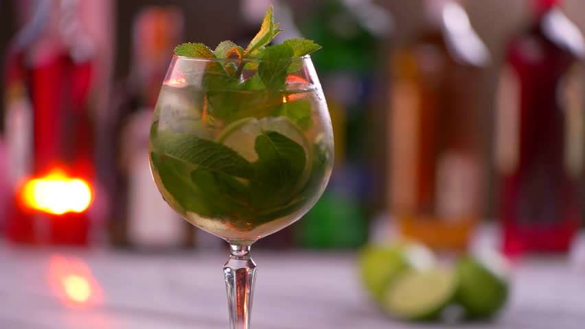 Rotating glass filled with drink. Slice of lime in beverage. Mint and citrus fruit. Hugo cocktail with elderflower syrup. Royalty-Free Stock Footage #17245936