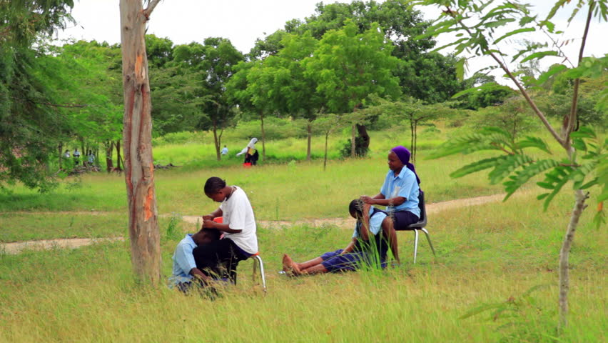 KENYA, AFRICA - CIRCA 2011: Two girls sitting outside putting corn rows into two