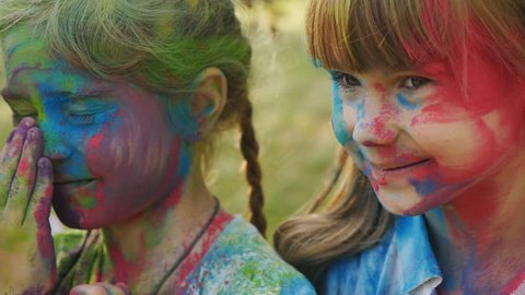 cute european child girls celebrate Indian holi festival with colorful paint