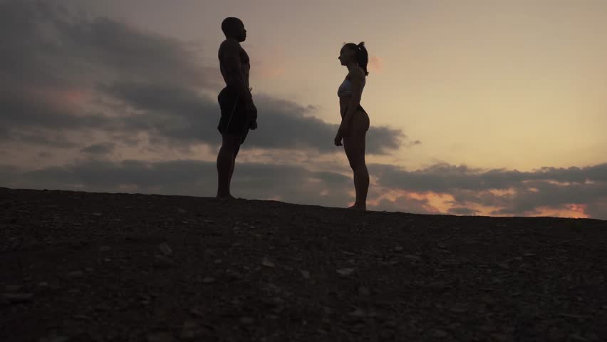 Silhouettes of fit mixed race couple stretching together on the rocky mountains background. Sport fitness concept | Shutterstock HD Video #17251408