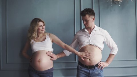 Pregnant couple near the wall. Pregnant woman and pregnant man