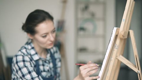 Woman painting a picture on easel
