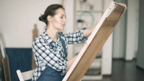 Young woman painting a picture on easel
