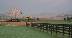 Turquoise lagoon in PERU with a parasol. Video footage in 4K resolution. Desert with the Lagoon La Encantada near Huacho, Peru.